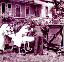 A l'hôpital d'Annecy, Francis RIERA (Pilote) et Paul ROUET (Mécanicien) chargent un blessé pour une évacuation avec l' Alouette 2 F-ZBAC Protection civile de la Base d'Annecy le 30 mai 1964 - Photo DR Archives GHSC Base d'Annecy