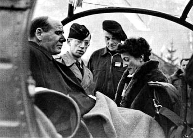 Alexis Santini assis dans l'Alouette 2 de l'Armée de l'air après récupération crash avec Valérie André épouse du commandant Santini, en arrière-plan, le commandant Le Gall avec le béret, 11 janvier 1957 - Photo DR