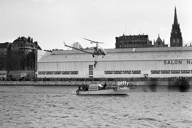Le pilote Henri Boris fait une démonstration de sauvetage (M. GARNIER sur l'échelle) à bord d'un hélicoptère Hiller 360 en s'approchant d'une vedette stationnée sur la Seine, le 2 avril 1950 à Paris lors du 1er salon national des Sports et du Camping - Photo Gettyimages